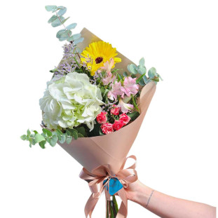 Buquê de flores da primavera com girassol, rosas, alstroemérias e hortênsias, envolto em papel com laço de cetim