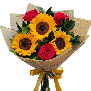 Buquê de três grandes girassóis e três rosas vermelhas com folhagem, envolto em papel rústico e amarrado com fita dourada.