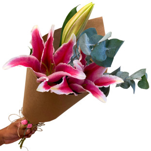 Buquê Cone Lírio Rosa destacando lírios rosa vibrantes envoltos em papel kraft rústico