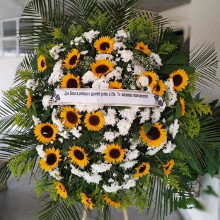 coroa de flores composta principalmente por girassóis e flores brancas menores