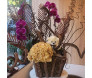 Arranjo de orquídeas roxas e flores secas com ursinho de pelúcia em cachepot de madeira, perfeito para decoração ou presente
