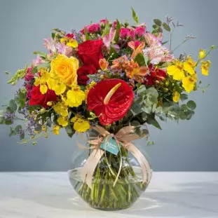 Arranjo de luxo com rosas vermelhas e amarelas, antúrio, orquídea chuva de ouro e folhagens em vaso de vidro arredondado - Ikebana Flores.