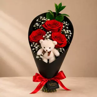 Buquê com Carinho contendo três rosas vermelhas, flores gipsofila brancas e um mini urso de pelúcia centralizado em embalagem cone preta com laço de cetim vermelho - Ikebana Flores BH.