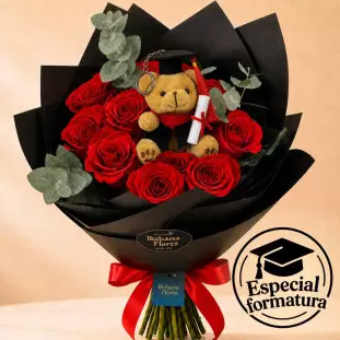 buque composto com 12 rosas vermelhas envolto em papel de presente preto acompanhado de um ursinho de pelúcia que está com vestes de formatura