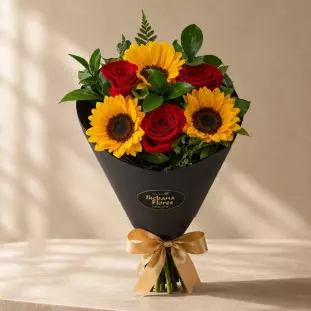Arranjo de flores em formato de cone preto que fica em pé, combinando girassóis amarelos e rosas vermelhas profundas com laço de cetim dourado - Ikebana Flores BH.