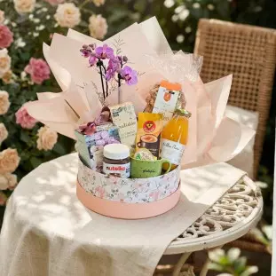 Vista lateral da Cesta de Café da Manhã na Box da Ikebana Flores BH, mostrando a orquídea, a caixa com padrão floral e os itens gourmet.