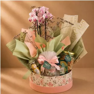 Cesta Elegance com mini orquídea, biscoitos, drip coffee, Ferrero Rocher e caneca em box floral