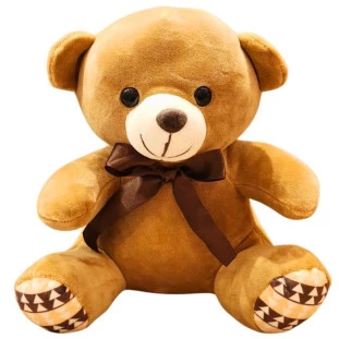 Urso de pelúcia marrom com laço de cetim marrom e detalhes nas patas