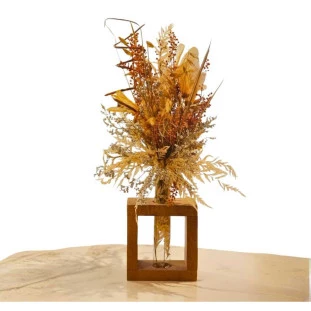 Arranjo de flores secas em vaso de vidro com estrutura cúbica de madeira