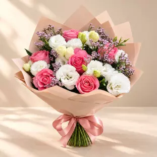 Buquê com flores rosadas e brancas, pequenas flores lilases, folhagens, papel rosado e laço