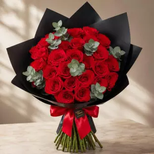 Grandioso Buquê Rubi de 30 rosas vermelhas premium com ramos de eucalipto fresco, envolto em embalagem de papel fosco preto com laço de cetim vermelho - Ikebana Flores BH.