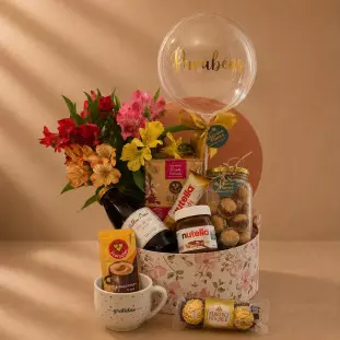 Cesta de café da manhã de aniversário com astromélias coloridas, balão Parabéns, Nutella, Ferrero Rocher, café, biscoitos e caneca