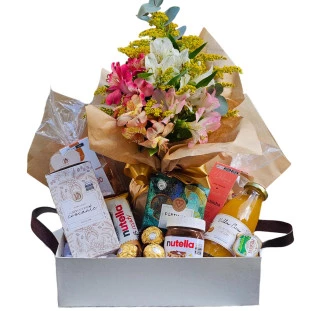 Cesta branca com flores de astromélias e itens selecionados de café da manhã.