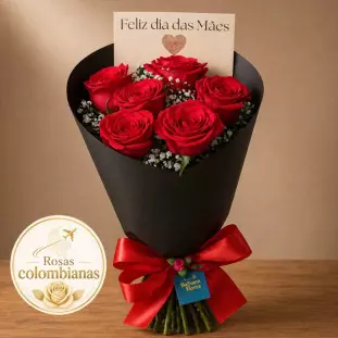 Buquê de seis rosas vermelhas envolto em embalagem de papel reforçado preto e laço vermelho em cima de mesa de madeira