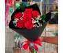 Close de buquê sofisticado de 6 rosas vermelhas de luxo em embalagem preta sendo segurado por uma pessoa - Ikebana Flores.