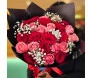 Buquê de 24 rosas Rosely em tons de vermelho e rosa com folhagens de eucalipto, embalado em papel marrom e amarrado com fita de cetim