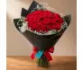 buquê de rosas vermelhas envolto em um papel cartonado preto e finalizado com laço vermelho