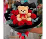 Arranjo romântico com ursinho de pelúcia de 23cm centralizado, cercado por 10 rosas vermelhas e ramos de eucalipto em embalagem de papel fosco preto com laço de cetim - Ikebana Flores BH.